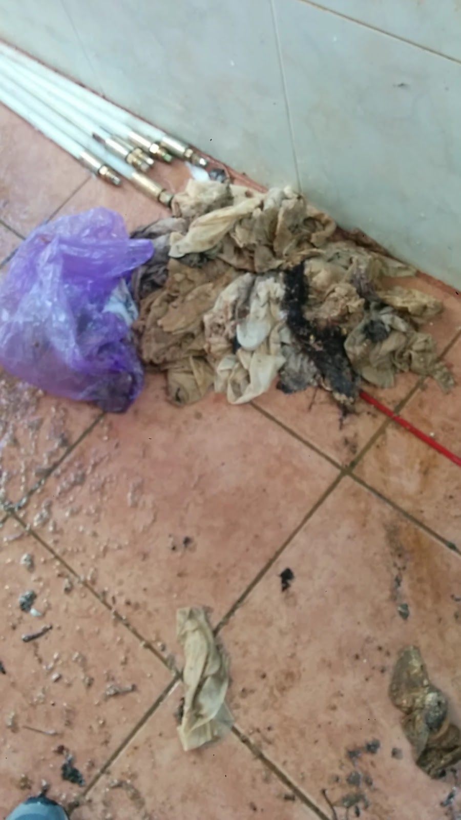 גוש רטוב של מגבונים ולכלוך מונח על רצפת אריחים אחרי שנשלף מתוך צנרת סתומה.